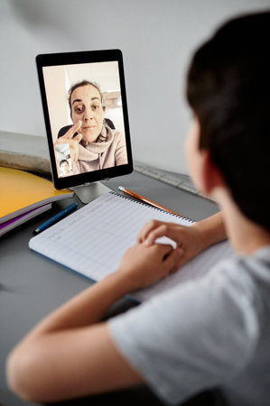 Happy little boy attending online classes from home. School education and social distance during...