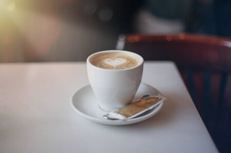 A cup of coffee on a table with a drawn heartの写真素材