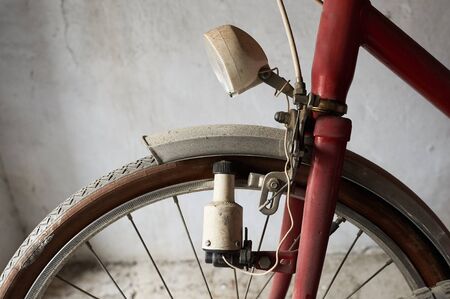 A wheel of a vintage bicycle with a dynamo and headlight in white backgroundの写真素材