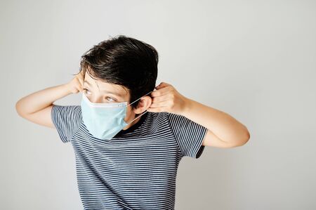 Nine-year-old boy putting on the virus protection mask alone.の写真素材