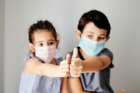 guys with thumbs up in victory for the virus, with unfocused faces in the backgroundの写真素材