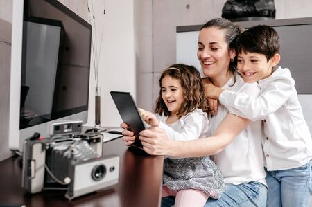 Middle-age mother with her children using digital tablet in workspaceの写真素材