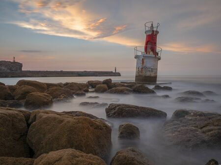 Lighthouse at sunset by the seaの写真素材