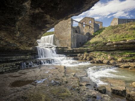 Views of an abandoned mill and waterfall from a caveの写真素材