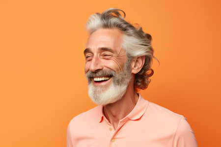 Portrait of happy senior man with gray hair and beard, isolated on orange background.の素材