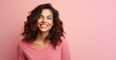 Portrait of happy smiling young woman in pink sweater over pink background.の素材