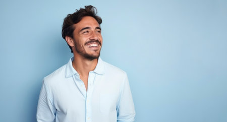 Portrait of a handsome young man laughing against blue background with copy space.の素材