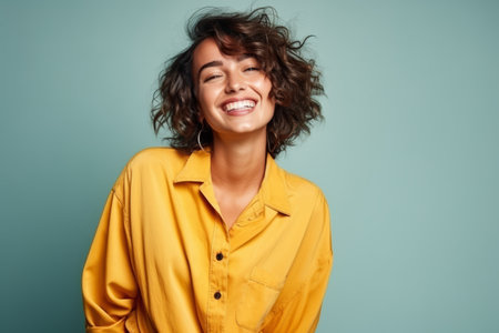Portrait of a beautiful happy young woman laughing, over blue background.の素材