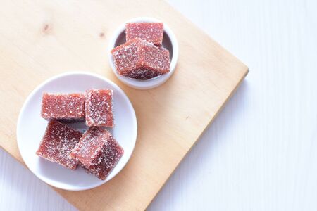 Guava sweet pieces with sugar in white plate on wooden backgroundの写真素材