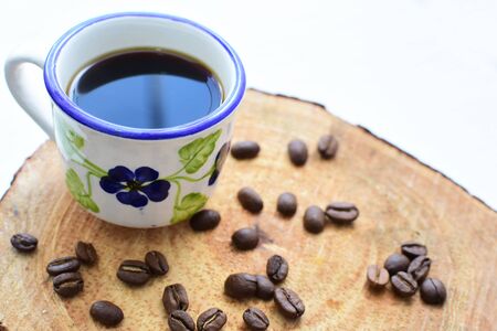 Cup of coffee, accompanied by coffee beans on wooden backgroundの写真素材