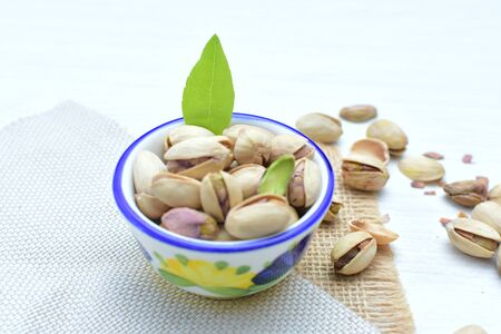 Whole, dried, open, whole, shelled and chopped dried pistachios displayed in containersの写真素材