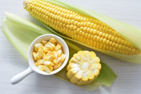 yellow sweet corn (cob) and green husk, chopped and shelled cornの写真素材