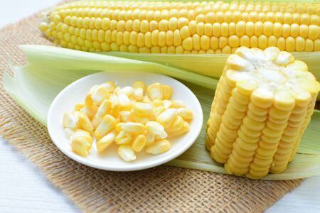 yellow sweet corn (cob) and green husk, chopped and shelled cornの写真素材