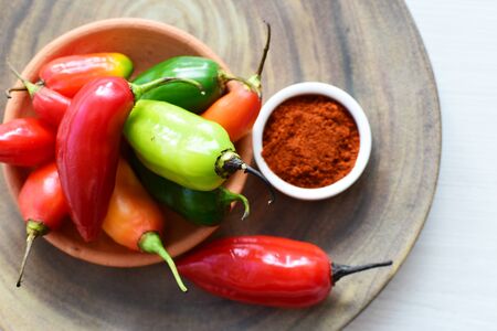 Capsicum Red and green and yellow bell peppers and chili peppers, displayed watered on a wooden surfaceの写真素材