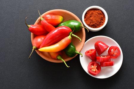Capsicum Red and green and yellow bell peppers and chili peppers, displayed watered on a wooden...