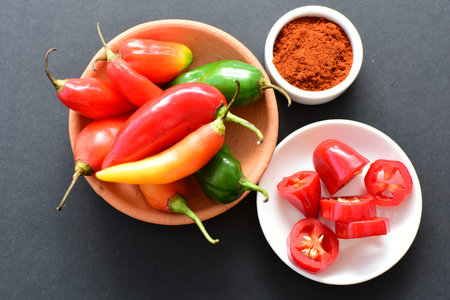 Capsicum Red and green and yellow bell peppers and chili peppers, displayed watered on a wooden...
