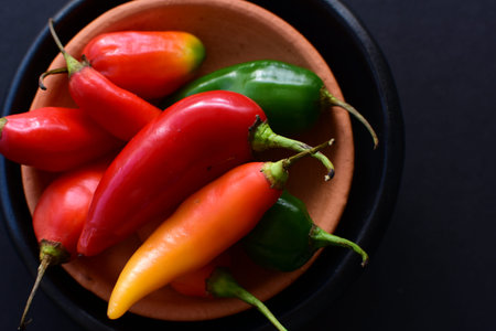 Capsicum Red and green and yellow bell peppers and chili peppers, displayed watered on a wooden...
