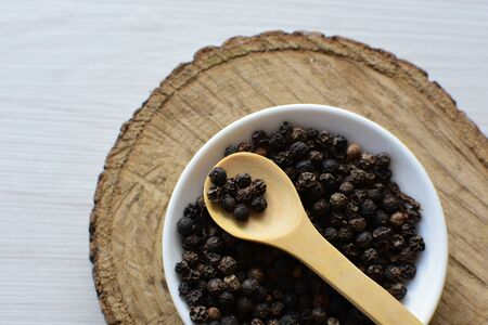 (Piper nigrum) Black pepper seeds, displayed in containers on wooden backgroundの写真素材