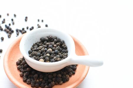 (Piper nigrum) Black pepper seeds, displayed in containers on wooden backgroundの写真素材