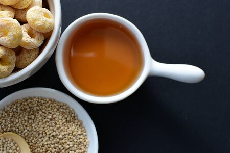 Quinoa cereal accompanied by quinoa seeds and honey on dark backgroundの写真素材