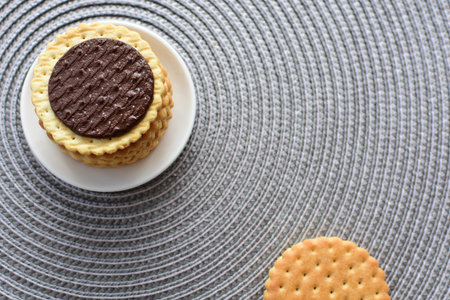 Double small vanilla cookies, with chocolate cream inside, open and closed cookies on white wooden...