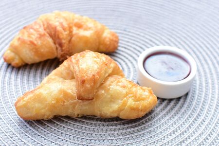 Small butter croissant accompanied by honey on white wooden backgroundの写真素材
