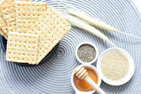 Soda crackers with healthy sesame whole and in pieces accompanied by honey on a flat backgroundの写真素材