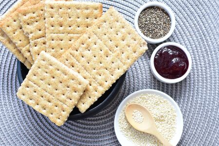 Soda biscuits with healthy sesame whole and in pieces accompanied by honey, jam and seeds on a flat backgroundの写真素材