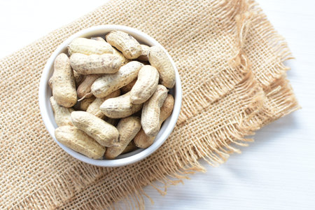 Arachis hypogaea - groundnut, whole, displayed in containers on white wooden background