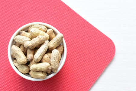 Arachis hypogaea - groundnut, whole, displayed in containers on white wooden background
