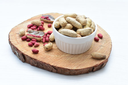 Arachis hypogaea - groundnut, whole, displayed in containers on white wooden background