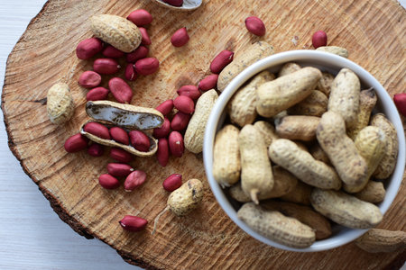 Arachis hypogaea - groundnut, whole, displayed in containers on white wooden background