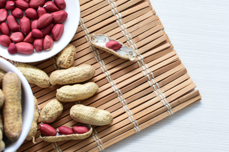 Arachis hypogaea - groundnut, whole, displayed in containers on white wooden background
