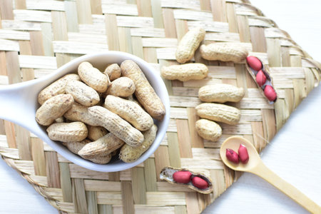 Arachis hypogaea - groundnut, whole, displayed in containers on white wooden background
