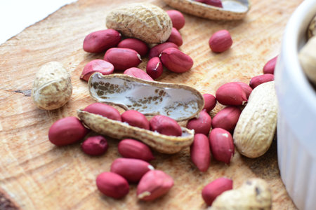 Arachis hypogaea - groundnut, whole, displayed in containers on white wooden background