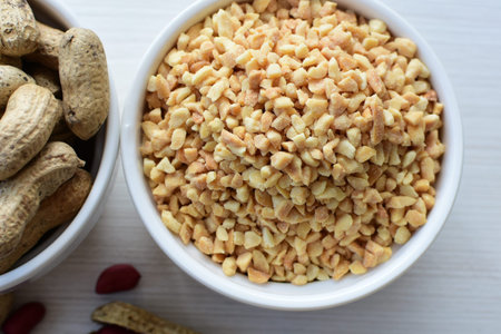 Arachis hypogaea - whole and chopped raw peanuts displayed in flat-bottomed containers