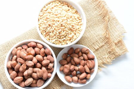 Arachis hypogaea - whole and chopped raw peanuts displayed in flat-bottomed containersの写真素材