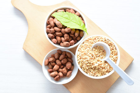 Arachis hypogaea - whole and chopped raw peanuts displayed in flat-bottomed containers