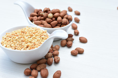 Arachis hypogaea - whole and chopped raw peanuts displayed in flat-bottomed containers