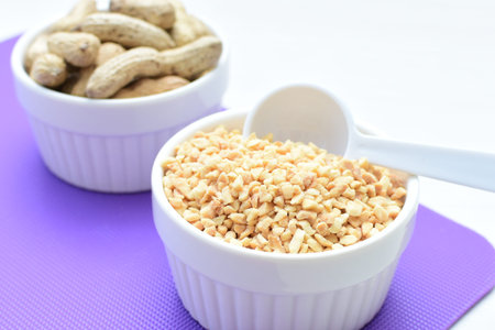 Arachis hypogaea - whole and chopped raw peanuts displayed in flat-bottomed containers