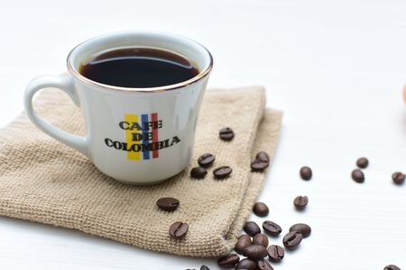 Traditional cup of coffee, accompanied by coffee beans on white backgroundの写真素材