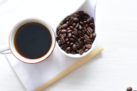 Traditional cup of coffee, accompanied by coffee beans on white background