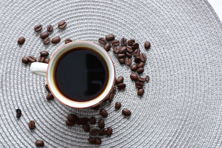 Traditional cup of coffee, accompanied by coffee beans on white background