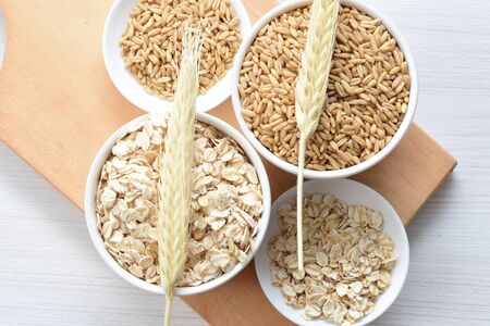 Avena sativa - Natural grain oats and flaked oats, displayed in containers showing the comparison of the 2 oatsの写真素材