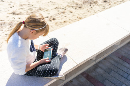 girl playing with the mobile on the beach