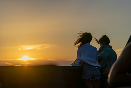 Serene Sunset Companionship: Two Friends Embracing the Evening Glowの写真素材