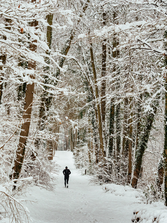 Jogger on snowy forest roadの写真素材