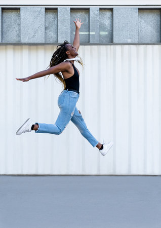 Retrato de una chica joven afroamericana saltando y divirtiendose. Estilo urbanoの写真素材