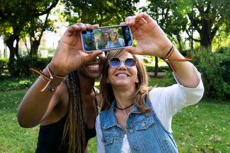 Capturing emotions, two happy friends of different races taking a selfie with their cell phone in a...