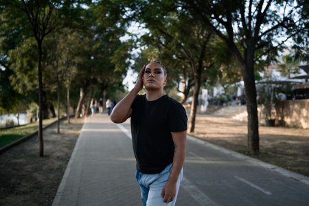 Portrait of a young non-binary person of Latin American origin looking at the camera while posing standing in the street. Concept of ethnic and gender diversity.の写真素材